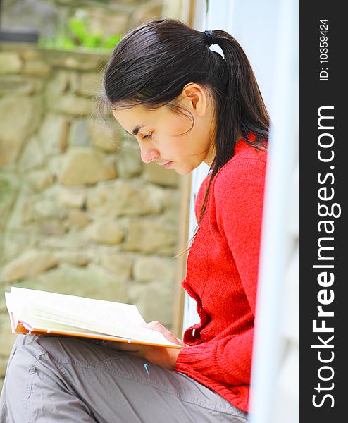 Young woman reading a book outdoors. Young woman reading a book outdoors.
