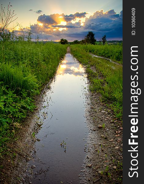 Pool on countryside road under sunset