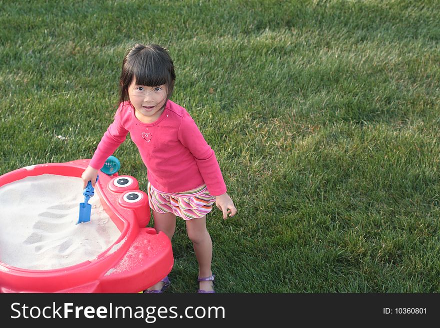 Cute young Asian girl playing with sandbox. Cute young Asian girl playing with sandbox