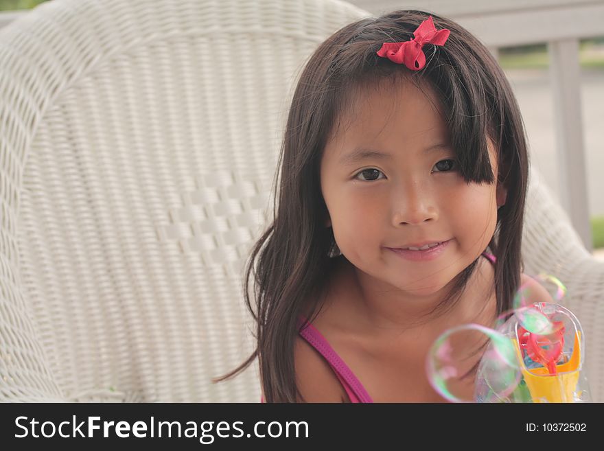 A cute little Asian girl makes bubbles with a bubble gun. A cute little Asian girl makes bubbles with a bubble gun.