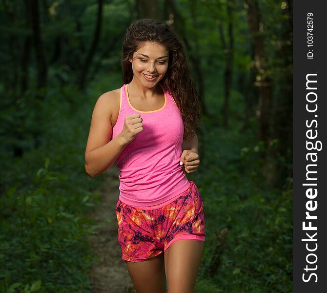 Active young fit woman runs in green forest on late summer after