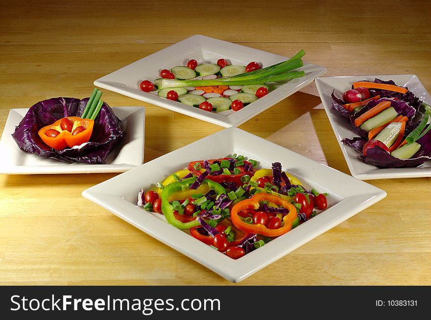 Many colorful vegetable plates arranged on wooden table.