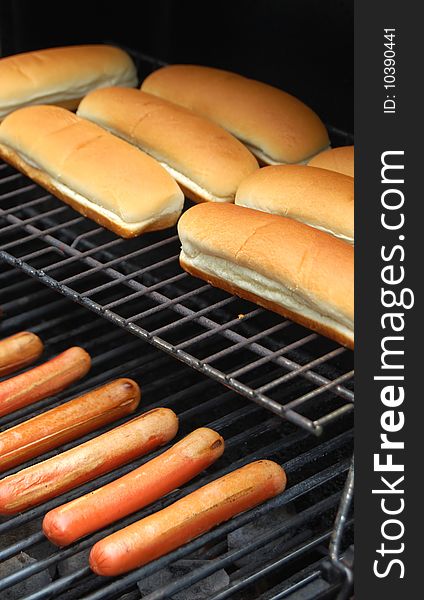 Hot dog sausages cooking on barbecue grill with bread rolls. Hot dog sausages cooking on barbecue grill with bread rolls.