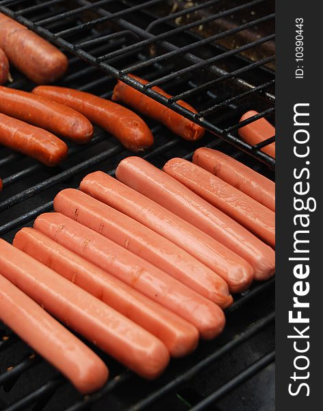 Rows of hot dog sausages on barbecue grill.