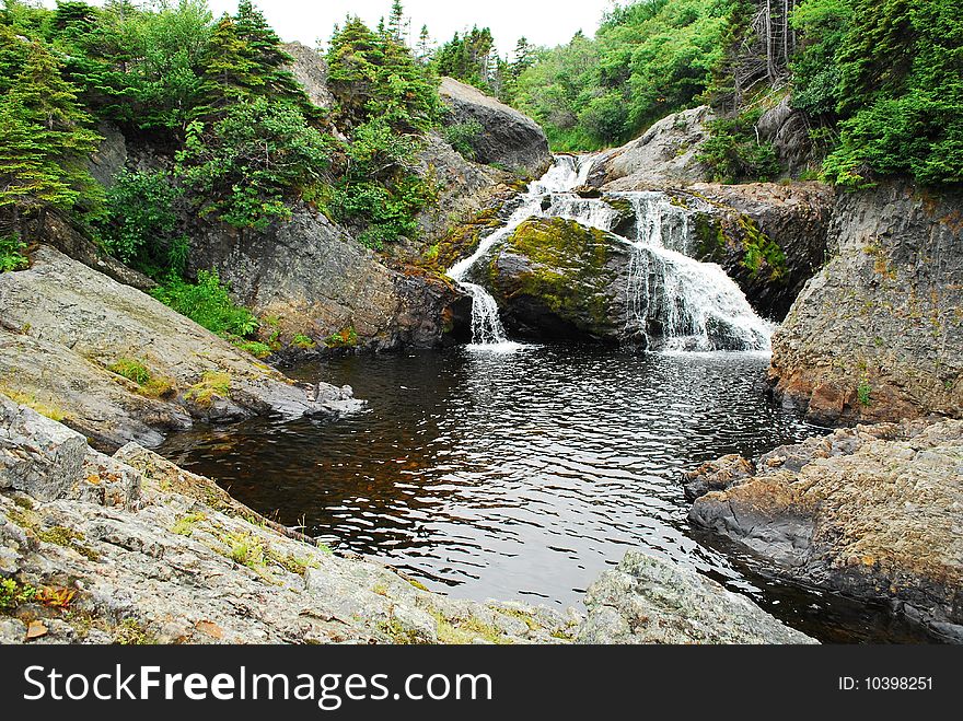 Scenic view of Flatrock river and waterfall with forest in background, Newfoundland, Canada. Scenic view of Flatrock river and waterfall with forest in background, Newfoundland, Canada.
