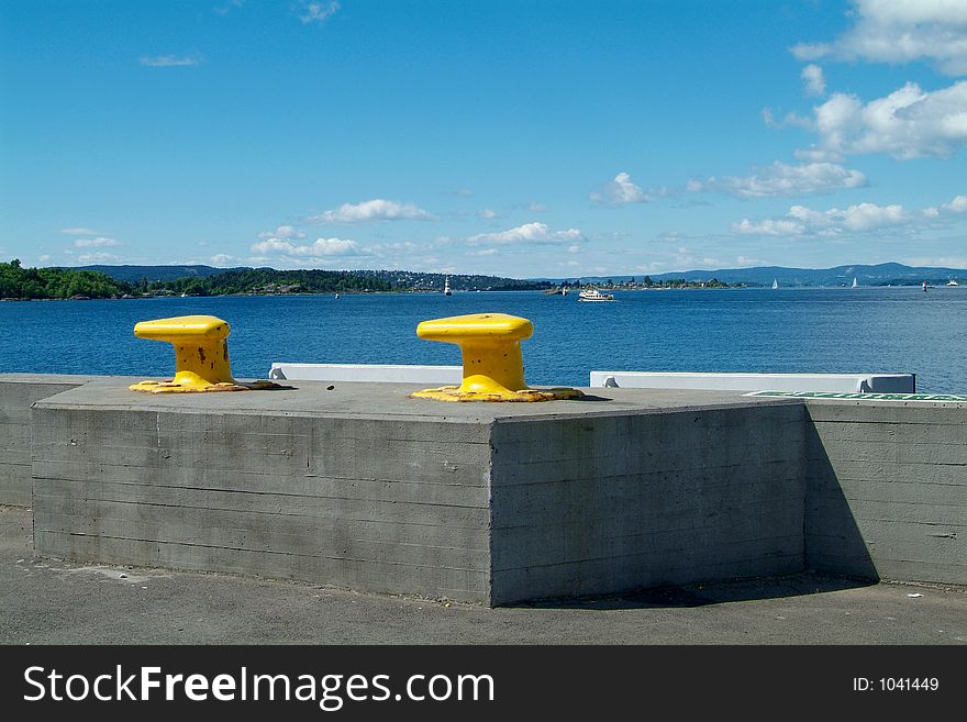 Two yellow cleats at the harbour of Oslo with view to the Oslofjord. Two yellow cleats at the harbour of Oslo with view to the Oslofjord.