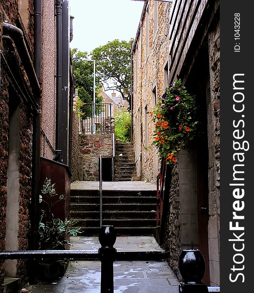 A quaint alley with steps in Scotland between traditional stone buildings.