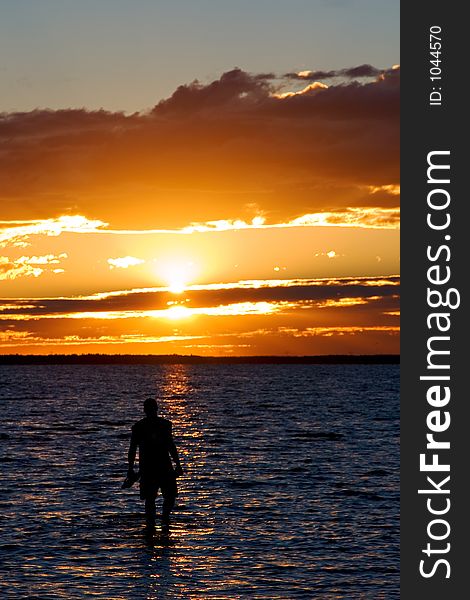 A young man wades into the lake at susnet. A young man wades into the lake at susnet.