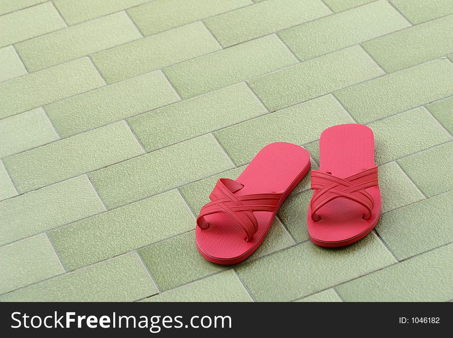 A pair of pink slippers on green tile floor