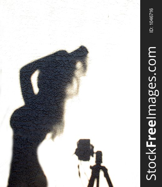 Shadow against stucco wall ~ female form and camera on tri-pod. Shadow against stucco wall ~ female form and camera on tri-pod