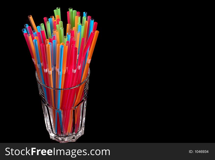 Vibrant colored straws in clear glass on black background. Vibrant colored straws in clear glass on black background