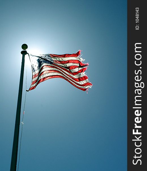 A flag waving in the breeze with the sun illuminating it from behind. A flag waving in the breeze with the sun illuminating it from behind