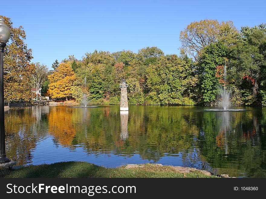 Lighthouse and fountains on calme pond in autumn. Lighthouse and fountains on calme pond in autumn.