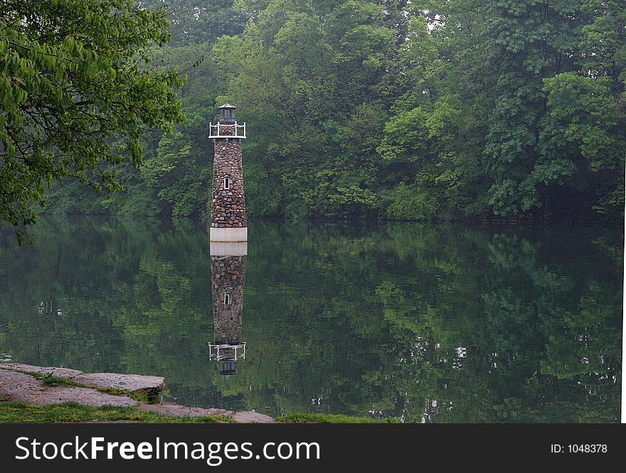 Lighthouse on calm pond in summertime. Lighthouse on calm pond in summertime.