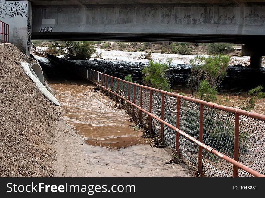 Flood waters flowing down a desert wash under the highway. Flood waters flowing down a desert wash under the highway.