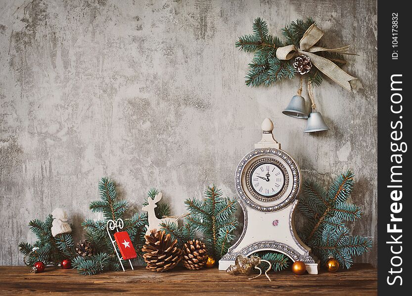 Christmas decor in the background of a concrete wall the old clock and fir cones on a wooden table. Christmas decor in the background of a concrete wall the old clock and fir cones on a wooden table