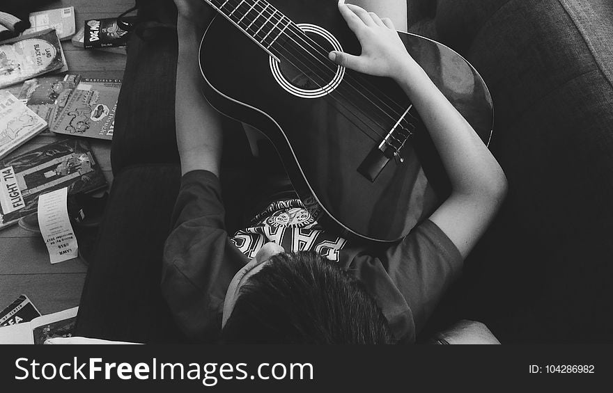 Man Playing Guitar Lying on Couch in Grayscale Photography