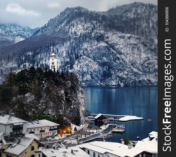 Snow Covered Mountain Houses Near Body of Water at Daytime