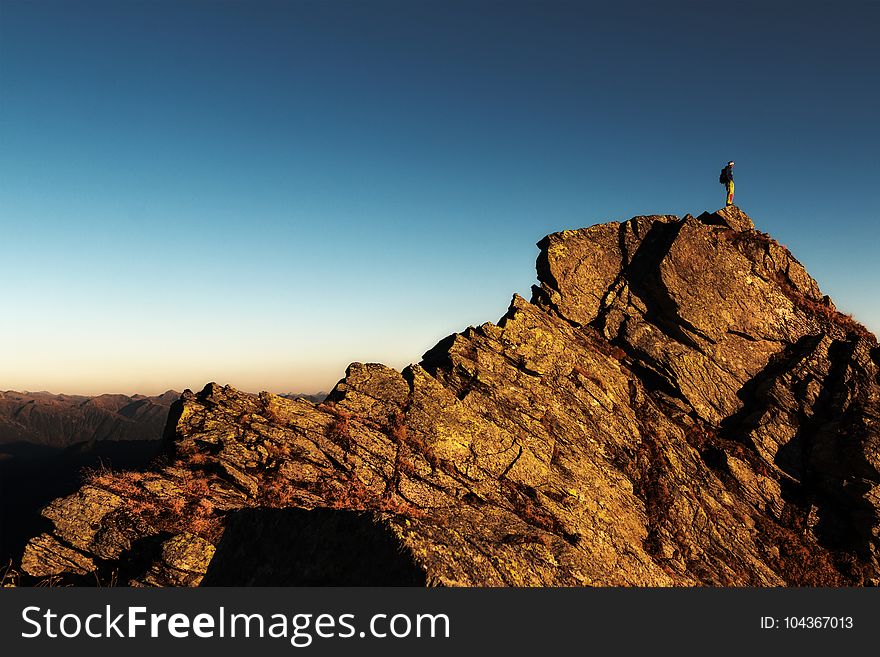 Man Standing on Top of Rock at Daytime