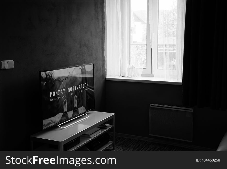 Gray Scale Photo of Flat Screen Tv on Top of Wooden Tv Rack