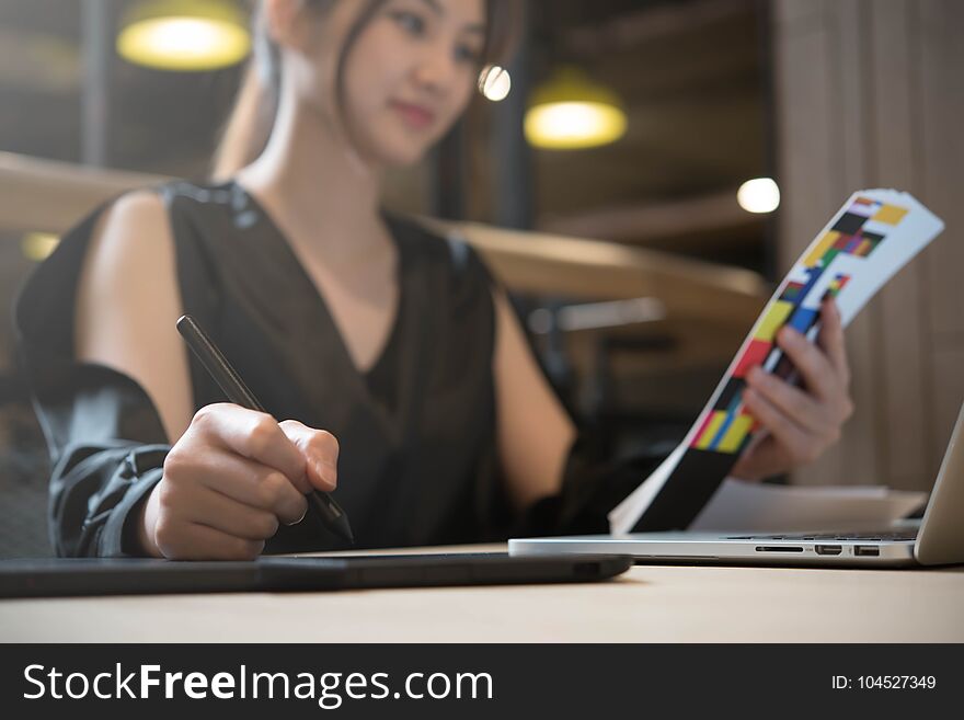 Beautiful asian woman designer in black dress working with mouse pen while look at color chart