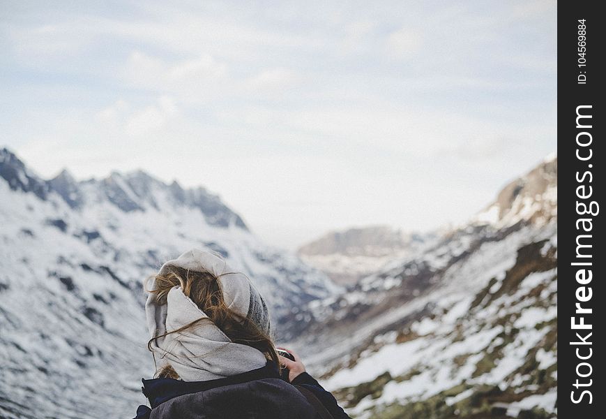 Person Wearing Black Jacket in Front of Mountain Filled With Snow