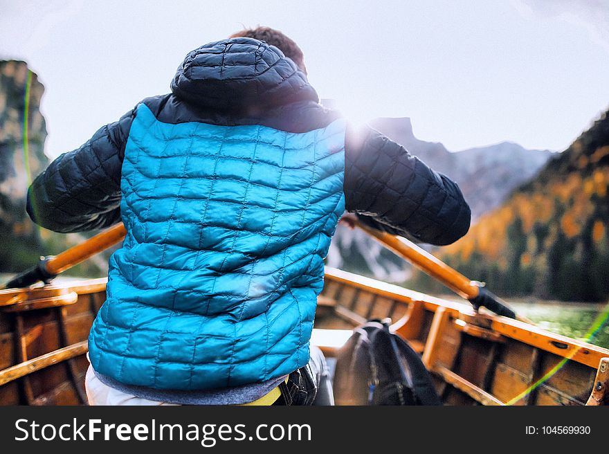 Man In Blue Vest Holding Paddle Sitting Inside Boat