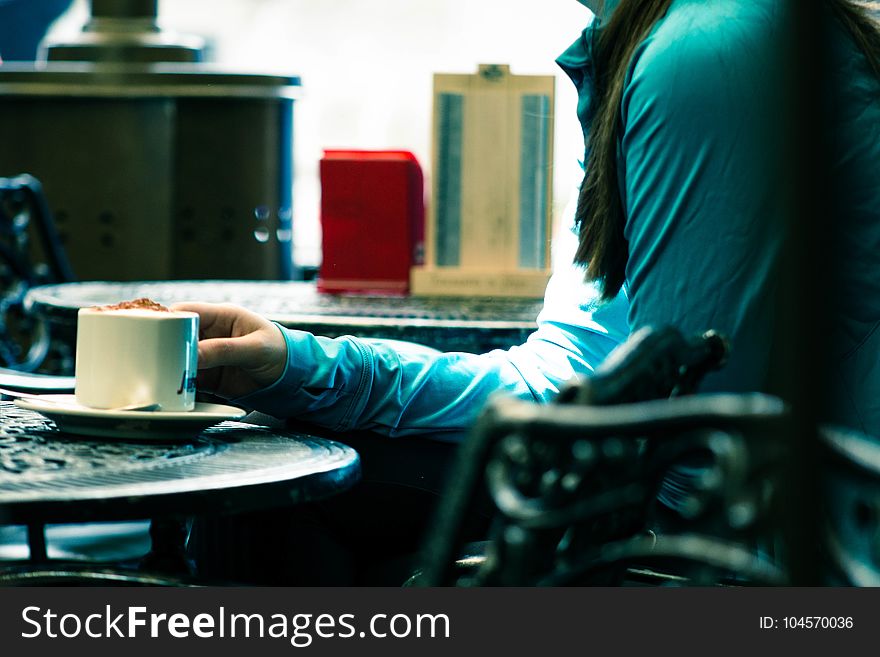 Person in Green Long-sleeved Top Sitting on Chair White Holding White Ceramic Mug