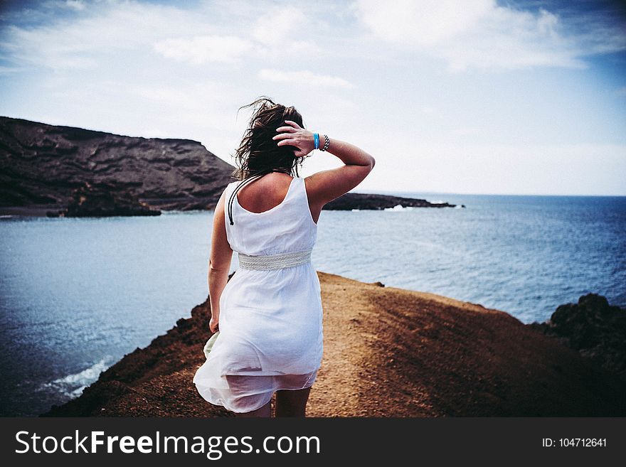 Woman Wearing White Sleeveless Mini Dress on Top of Brown Sand Near Body of Water