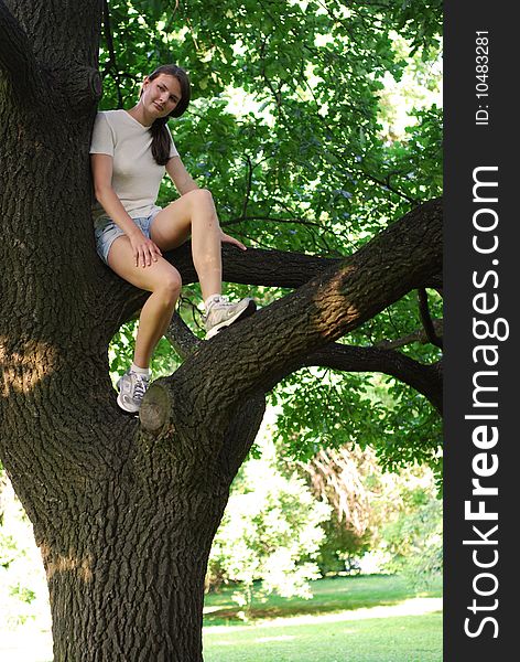 Girl sitting on the oak; background is blurred