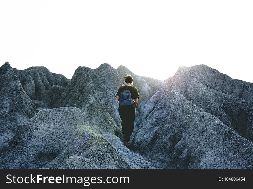 Man in Black Crew Neck Shirt and Pants Walking on Gray Mountain Formations