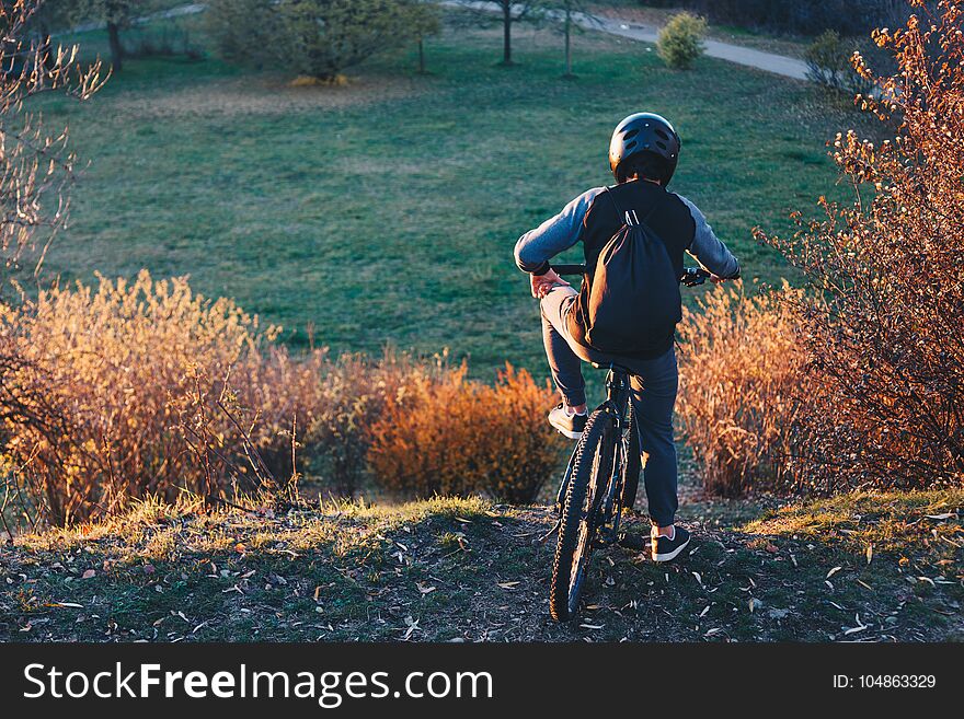 Mountain biker stands on the edge of a hill at sunset before riding downhill - Success and winning concept.