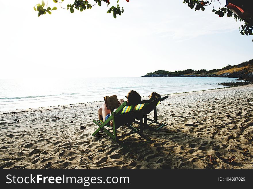 People Lying On Green Wooden Lounger Chairs On Beach