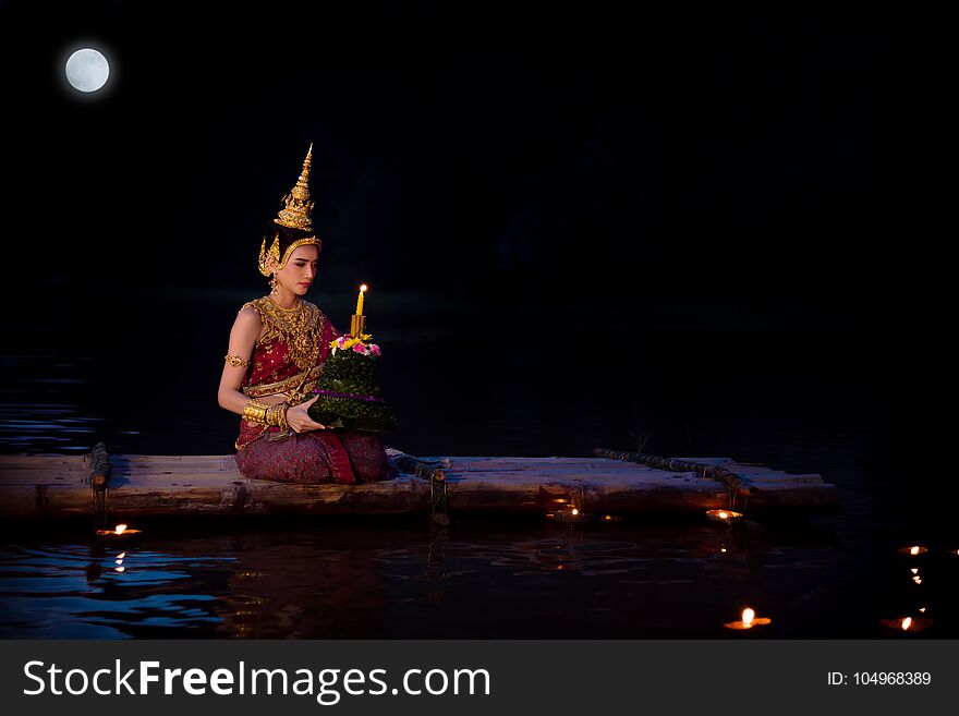 Beautiful asian girl in Thai traditional dress sitting on floating raft