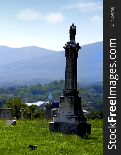 A cemetery on the side of a hill overlooking mountains and a country church in the background. A cemetery on the side of a hill overlooking mountains and a country church in the background.