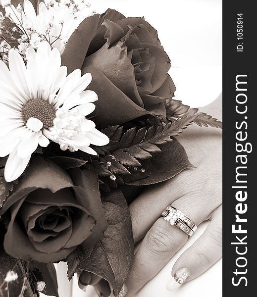 Bride's wedding ring hand and bouquet closeup in sepia