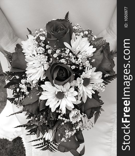 Bride Holding Her Wedding Bouquet Against Her Dress In Black And White