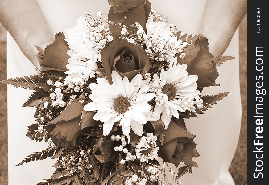 Bride holding her wedding bouquet against her dress - horizontal