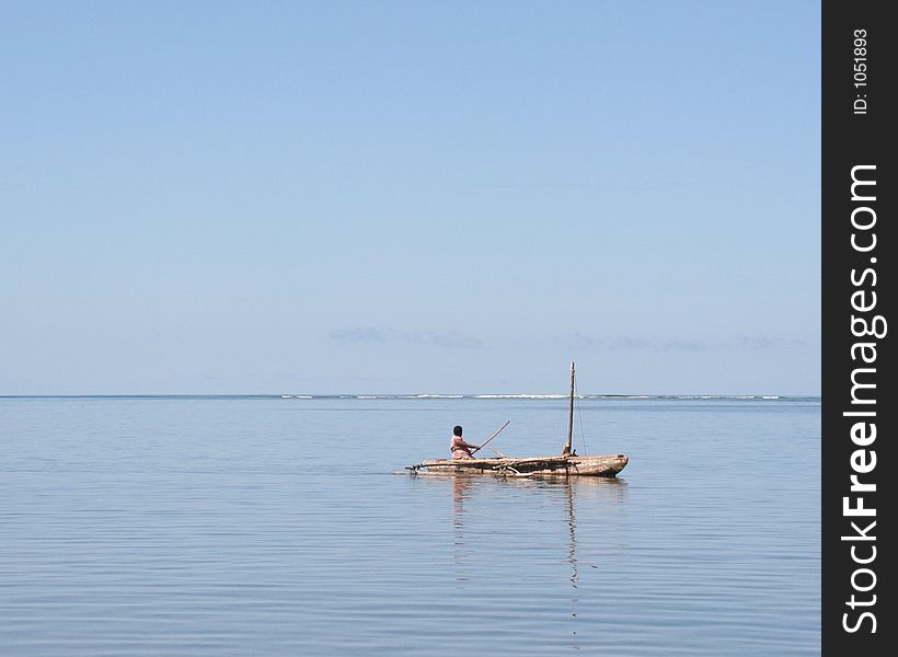 Pacific islander paddling a canoe across open sea to get to work on another island. In the evening they sail back using the prevailing wind. Pacific islander paddling a canoe across open sea to get to work on another island. In the evening they sail back using the prevailing wind.