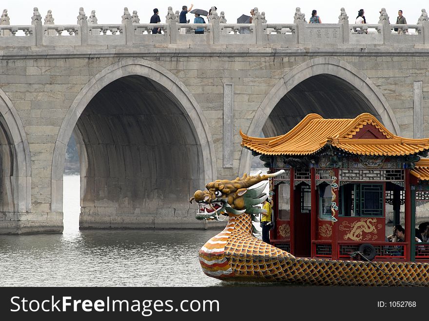 A dragon boat next to an ancient bridge in a scenery park