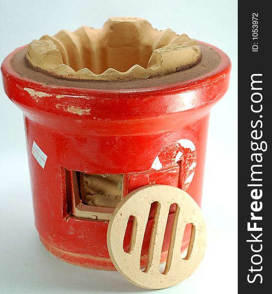A small tranditional red chinese charcola stove used in a house hold. A small tranditional red chinese charcola stove used in a house hold