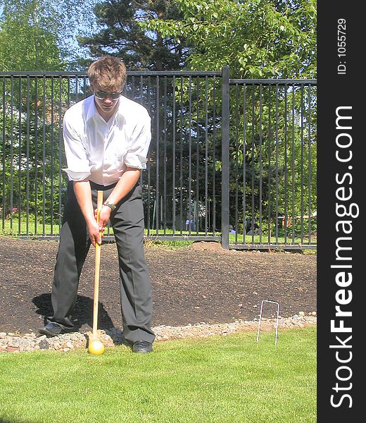 A picture of jonny lining up for the shot in a casual game of back yard croquet. A picture of jonny lining up for the shot in a casual game of back yard croquet