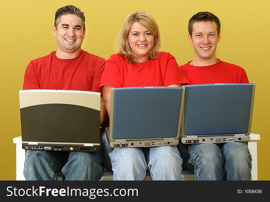 Three people working on laptops siiting on white bench over yellow background. Full body. Ages 32, 26, 18. Three people working on laptops siiting on white bench over yellow background. Full body. Ages 32, 26, 18.