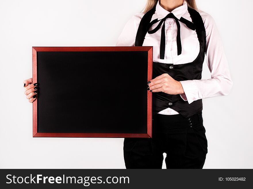 Young elegant business female with tie bow and white shirt holding blank drawing blackboard in hands and space for text on board. Close up. Business and education concept. Young elegant business female with tie bow and white shirt holding blank drawing blackboard in hands and space for text on board. Close up. Business and education concept.