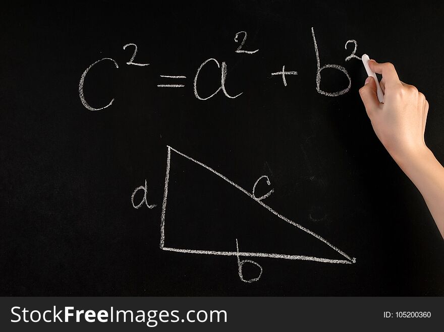 Girl hand write Pythagoras Theorem and angled triangle with on school blackboard with white chalk
