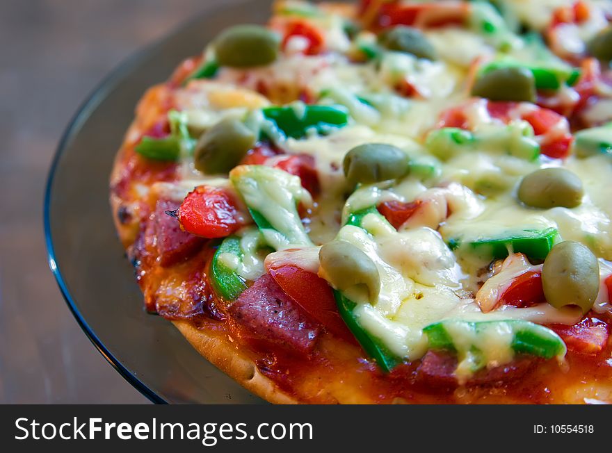 Closeup pizza with salami, tomatoes, green pepper, olives and cheese