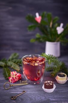 Fruit And Hibiscus Tea In Transparent Cup, Luxury Chocolates Candy And Christmas Tree Branch On A Dark Background Stock Images