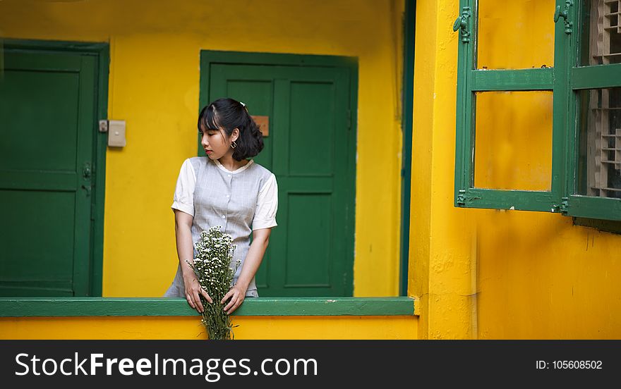 Woman Holding Flower Standing Behind Door