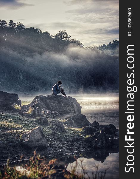 Man In Gray Shit Sitting On Rock Boulder