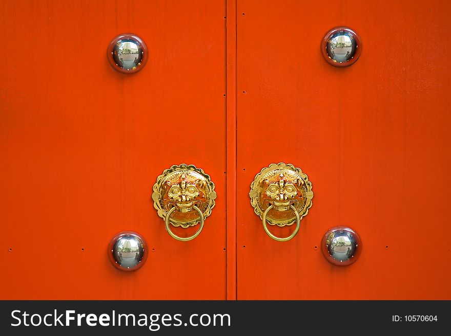 Red chinese door with a lion head door knocker at the entrance of old temple in city center. Red chinese door with a lion head door knocker at the entrance of old temple in city center